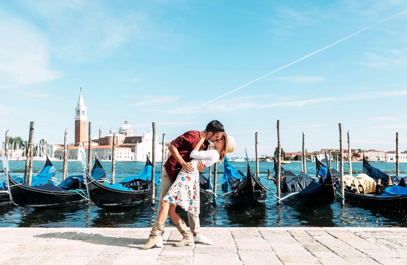 Weekend romantico, coppia che si bacia con sfondo di barche