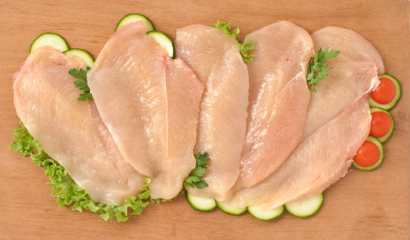 Fette di pollo distese su insalata e zucchine