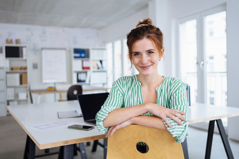 acconciature per il lavoro; donna sorridente in ufficio con i capelli legati
